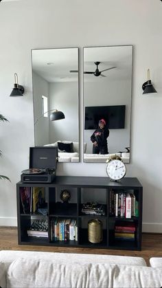 a living room with a couch, mirror and bookshelf in front of it