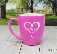 a pink coffee cup sitting on top of a wooden table