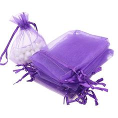 three bags filled with white balls sitting on top of purple organe bag covers and ties