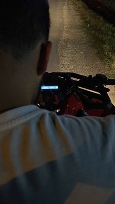 a man riding on the back of a motorcycle down a street at night with his cell phone in hand