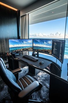 two computer monitors sitting on top of a desk in front of a window with ocean view