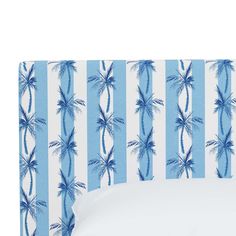 a bed with blue and white palm trees on the headboard, against a striped wallpaper