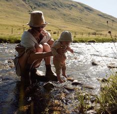 a woman and her baby are playing in the water on a sunny day with mountains in the background