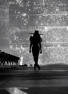 a black and white photo of a person walking in front of an audience at a concert