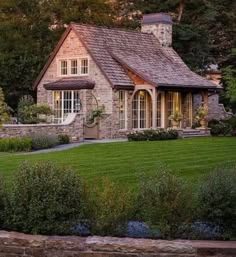 a stone house in the middle of a lush green field