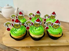 three cupcakes with green frosting on a cutting board