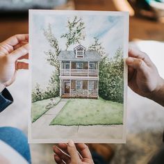 two hands holding up a drawing of a house