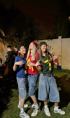 three young people standing next to each other on top of a lush green field at night