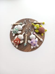 several crocheted sea animals are on a wooden board with beads and chains hanging from it