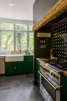 a kitchen with green cabinets and an oven next to a sink in the middle of the room