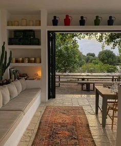 a living room filled with furniture next to a patio covered in plants and potted plants