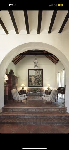 a living room filled with furniture and a painting on the wall above it's doorway