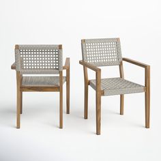 two wooden chairs sitting next to each other on a white surface with no one in it