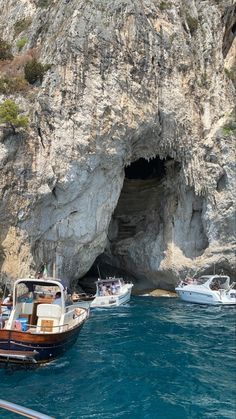 several boats in the water near a cave