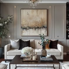 a living room filled with furniture and a chandelier above a coffee table in front of a painting