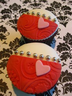 two red and white cupcakes with hearts on them