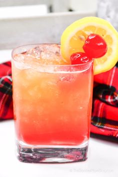 a close up of a drink in a glass with a cherry on the rim and a lemon slice