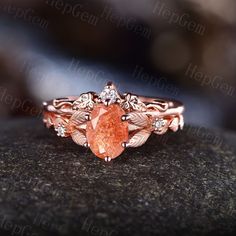 a ring with an orange stone surrounded by leaves