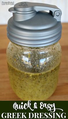 a jar filled with green dressing sitting on top of a wooden table