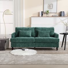 a green couch sitting on top of a rug in a living room next to a table