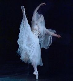 a ballerina is dressed in white and dancing with her arms stretched out to the side