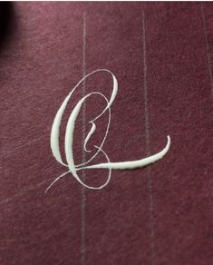 the letter g is written in cursive writing on a maroon background with vertical lines