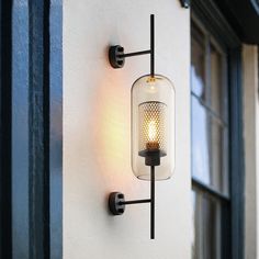 a wall mounted light on the side of a building with a window in the background