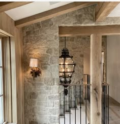 a light hanging from the side of a stone wall next to a stair case in a home