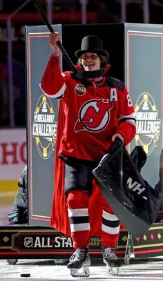 a hockey player is walking on the ice with his glove in one hand and an umbrella in the other