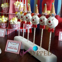 there are some cake pops with clown faces on them and candy sticks in front of them