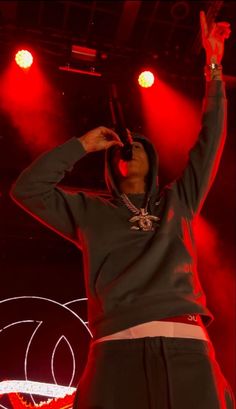 a man standing on top of a stage with his hands in the air and headphones up