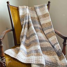 a chair with a blanket on top of it in front of a white and brown wall