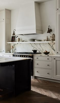 a kitchen with white cabinets and marble counter tops, along with an island in the middle