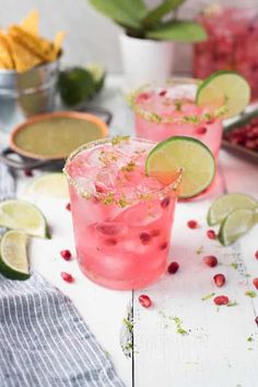 two glasses filled with pink lemonade, lime and pomegranate garnish