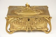 an ornately decorated gold jewelry box on a white surface with no people around it