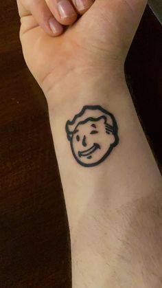 a person with a small tattoo on their wrist that has an image of a man's face