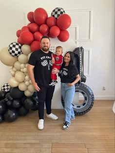 a man and woman standing next to each other in front of balloons on the wall