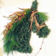 a stuffed animal made out of fake grass and other things hanging on the side of a wall