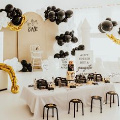 a table with black and white balloons in the shape of an arch, some gold foiled letters on it