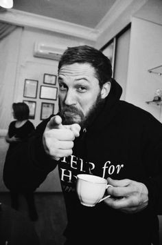 a black and white photo of a man holding a coffee cup