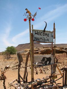 a welcome sign in the desert with an elephant on it's back and a flag flying above it