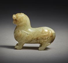 a small carved animal sitting on top of a gray surface with an intricately designed tail