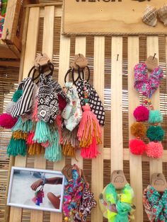 several different types of hair accessories hanging on a wooden rack in front of a sign