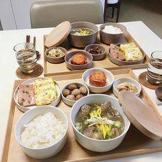 a wooden tray topped with bowls filled with food