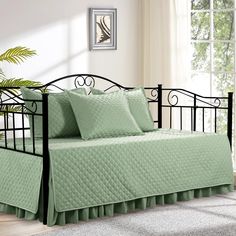 a day bed with green sheets and pillows