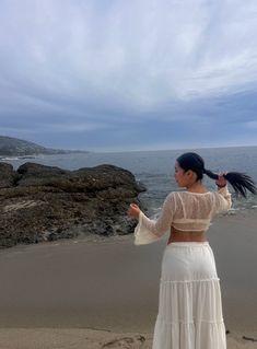 a woman standing on top of a beach next to the ocean