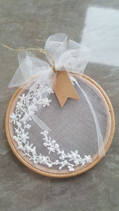 a white doily with a brown tag hanging from it's side on a wooden hoop