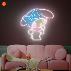 a living room with pink couches and a neon hello kitty sign on the wall