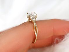 a close up of a person's hand holding a ring with a diamond on it