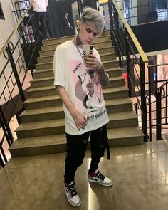 a young man standing in front of some stairs looking at his cell phone